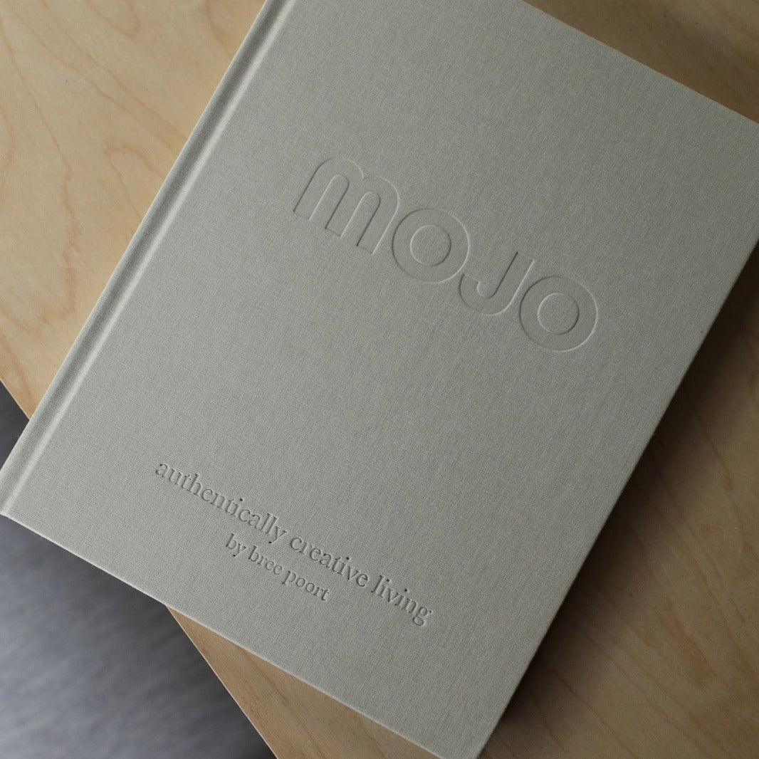 Photo of front cover of the Mojo book on top of a light grained wood table.